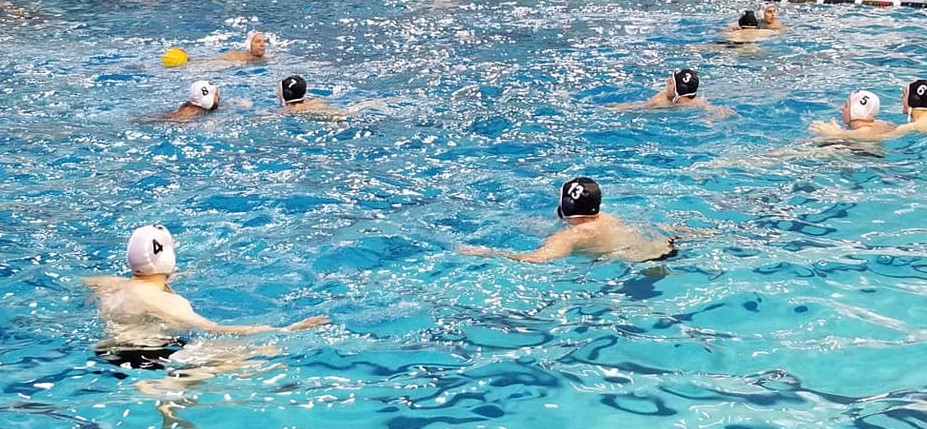 Water polo player at 3 position with the ball looking to set up the offense.